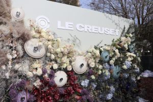 Sign that says Le Creuset with beautiful flowers and pot lids decorating the sign